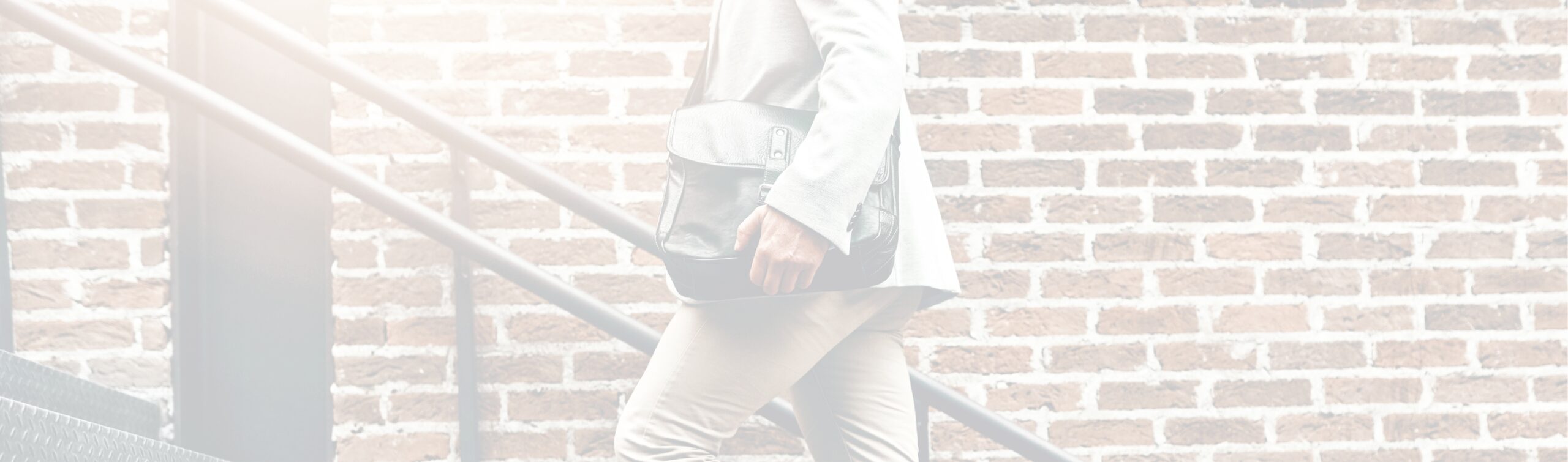 Man walking up stairs next to brick will carrying briefcase