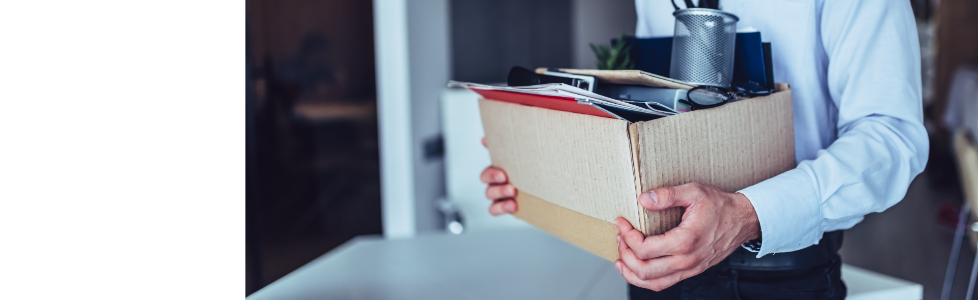 Man standing in office with cardboard box filled with personal office supplies
